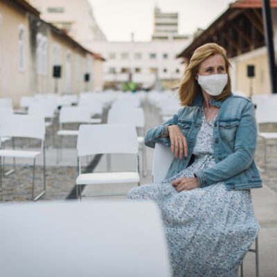 woman in blue denim jacket and white and black dress sitting on white concrete fence during