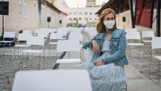 woman in blue denim jacket and white and black dress sitting on white concrete fence during