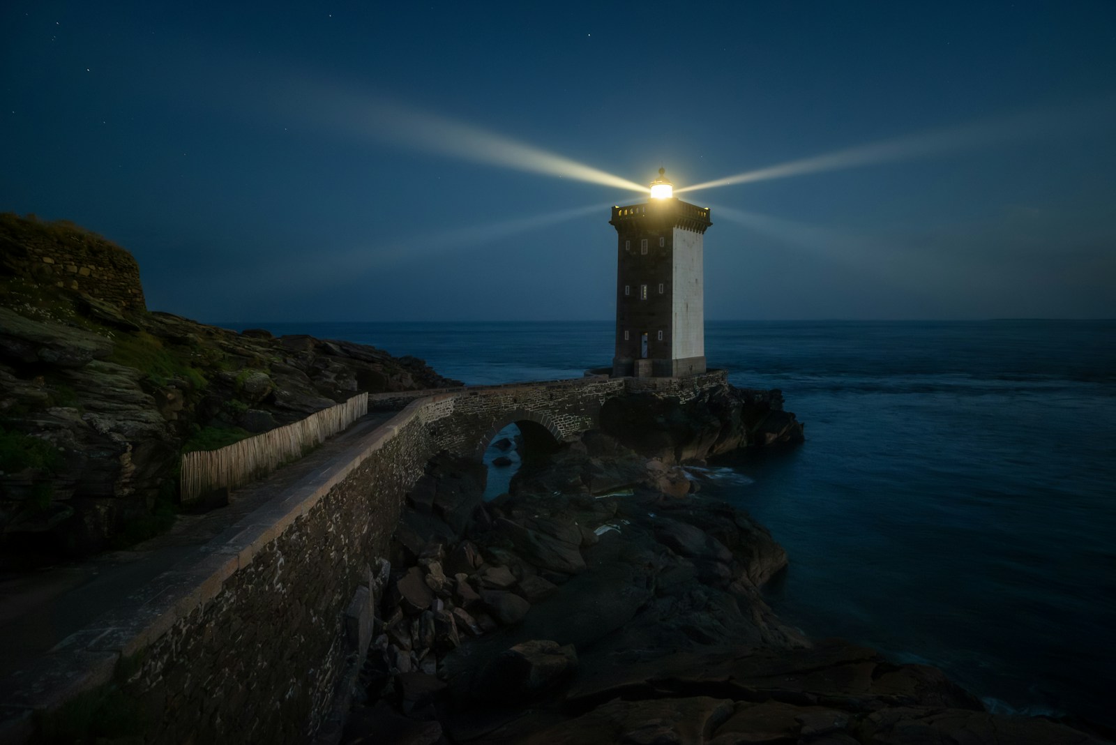 Lighthouse shining light on a rocky coast at night